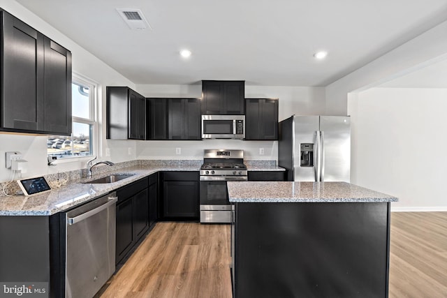 kitchen with visible vents, a sink, a center island, appliances with stainless steel finishes, and dark cabinets