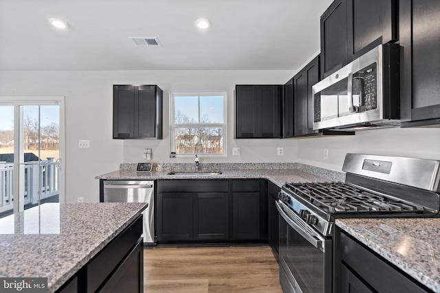 kitchen with a sink, dark cabinets, visible vents, and stainless steel appliances