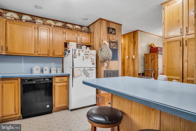 kitchen with light floors, dishwasher, a breakfast bar area, light countertops, and freestanding refrigerator