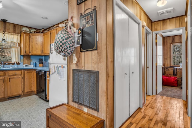 kitchen featuring wooden walls, visible vents, black dishwasher, brown cabinets, and freestanding refrigerator