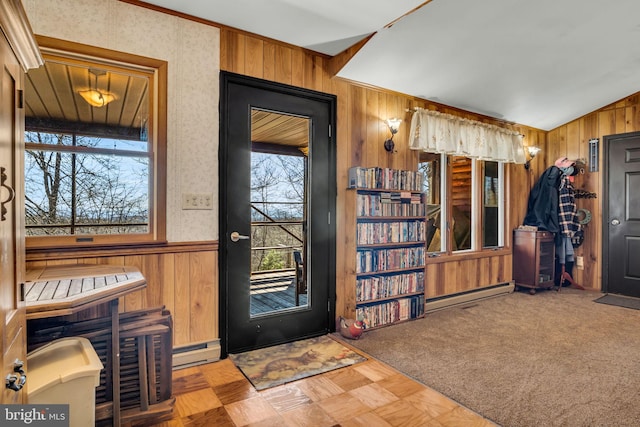 entryway featuring a baseboard radiator, a wainscoted wall, wood walls, and vaulted ceiling