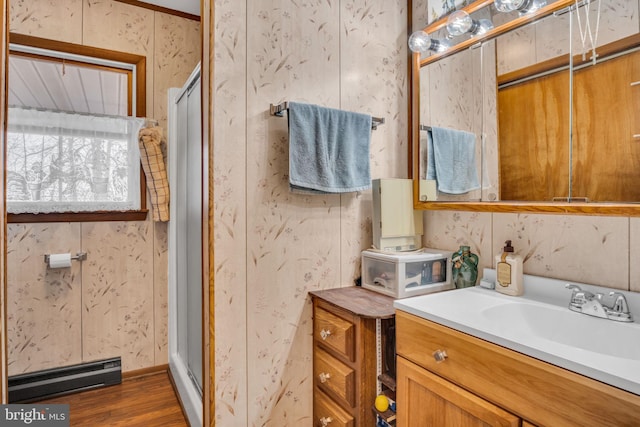 bathroom featuring vanity, wood finished floors, a stall shower, and a baseboard radiator