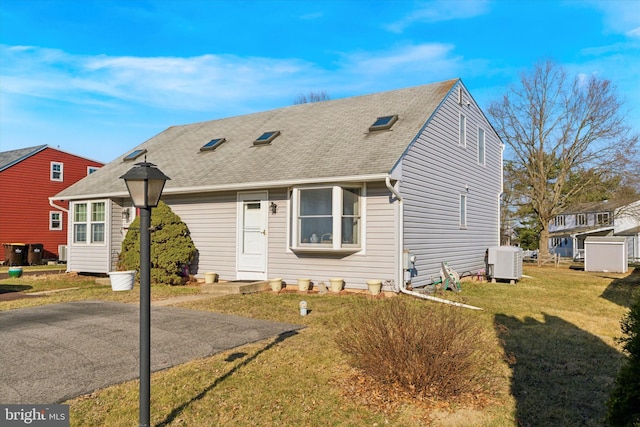 view of front of home featuring central air condition unit, a front lawn, and roof with shingles