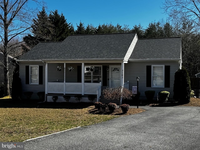 single story home featuring a porch, a front lawn, and a shingled roof