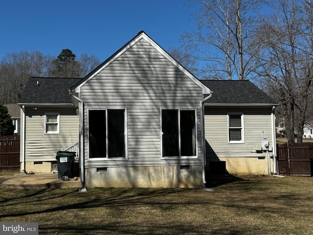 rear view of property with crawl space, a shingled roof, a yard, and fence