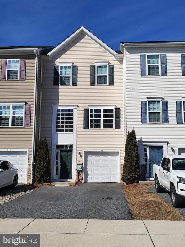 townhome / multi-family property featuring aphalt driveway and an attached garage