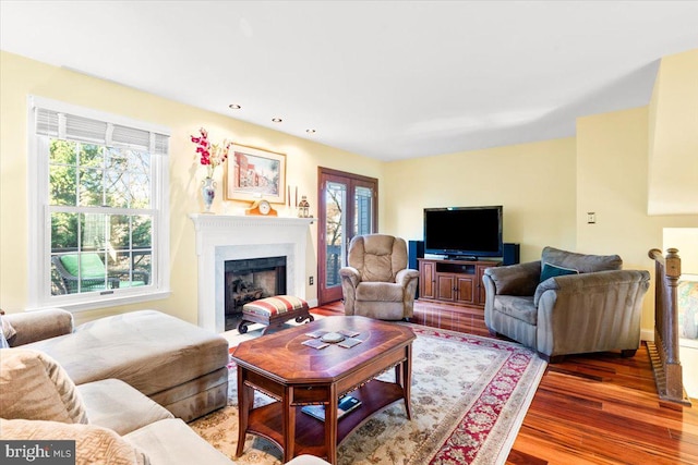 living room featuring recessed lighting, a fireplace with flush hearth, a healthy amount of sunlight, and wood finished floors