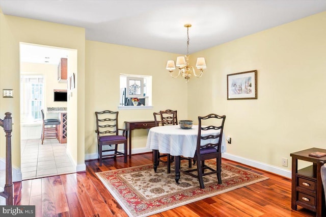 dining area with a chandelier, baseboards, and wood finished floors