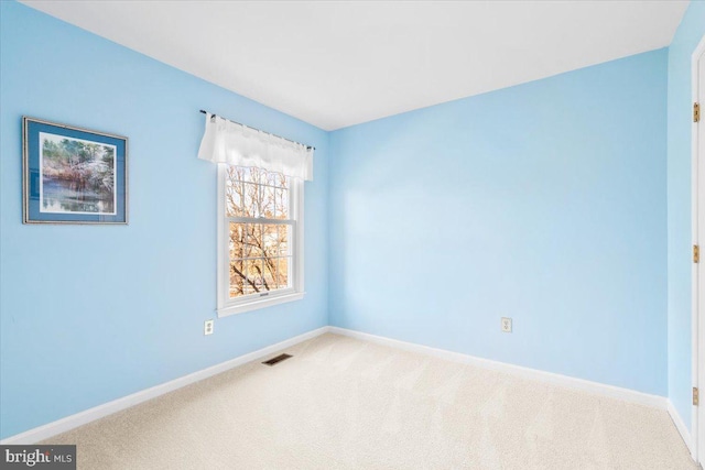 carpeted spare room with visible vents and baseboards