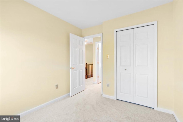 unfurnished bedroom with a closet, baseboards, and light colored carpet