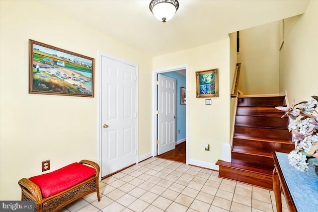 interior space with stairs, light tile patterned floors, and baseboards