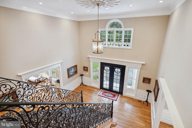 foyer entrance featuring ornamental molding, french doors, an inviting chandelier, and wood finished floors