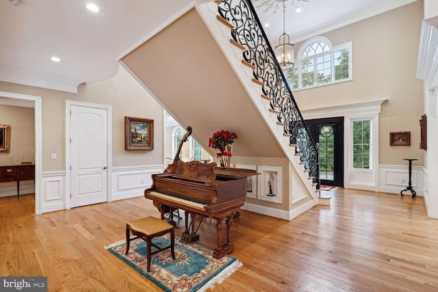 entrance foyer with light wood-type flooring, stairway, a notable chandelier, and a healthy amount of sunlight