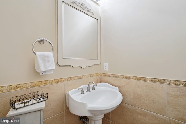 bathroom featuring tile walls, a wainscoted wall, and a sink