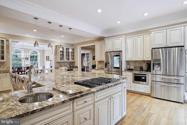 kitchen with light wood-type flooring, a sink, tasteful backsplash, appliances with stainless steel finishes, and glass insert cabinets