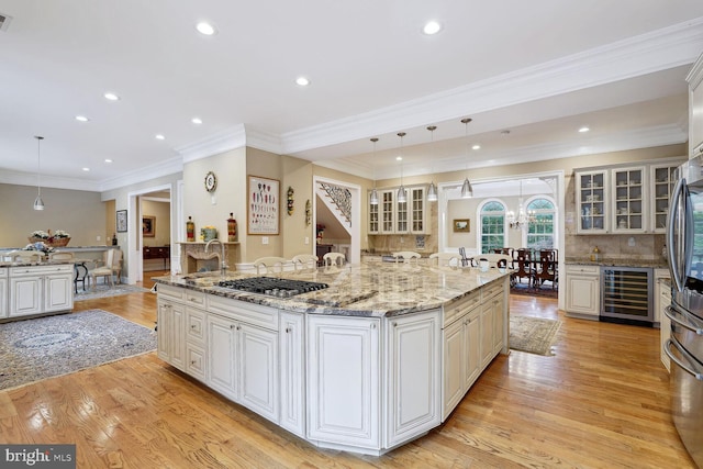 kitchen with decorative backsplash, light wood finished floors, beverage cooler, and stainless steel gas cooktop