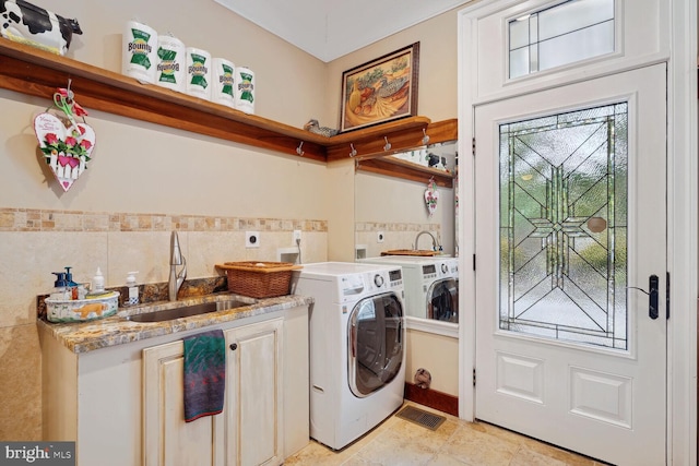 washroom featuring a wealth of natural light, cabinet space, washer and dryer, and a sink