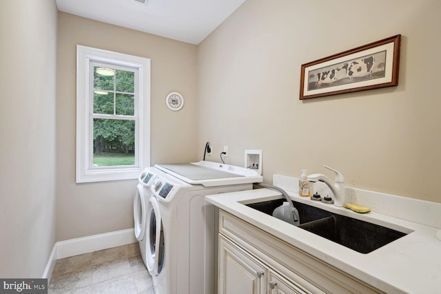 clothes washing area featuring washer and dryer, a sink, cabinet space, light tile patterned floors, and baseboards