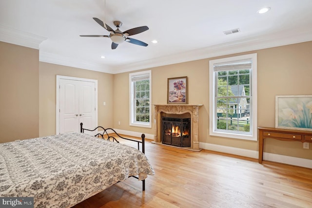 bedroom featuring light wood-type flooring, visible vents, multiple windows, and crown molding