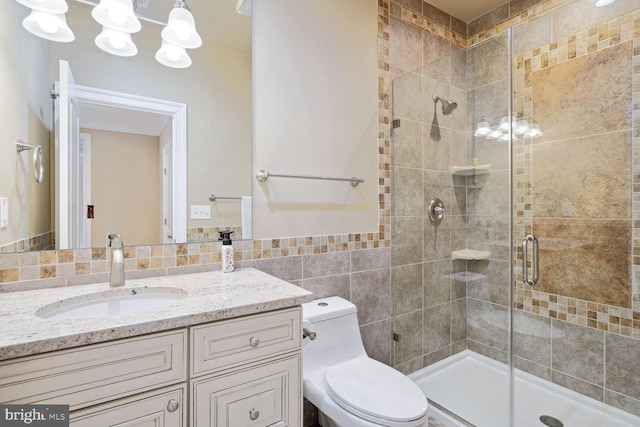 bathroom featuring toilet, a stall shower, tile walls, and vanity