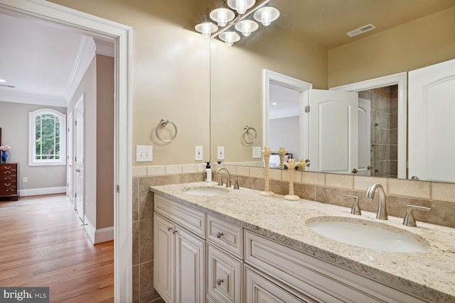 bathroom with tile walls, crown molding, visible vents, and a sink