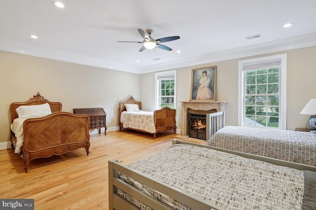 bedroom with visible vents, multiple windows, light wood-style flooring, and ornamental molding