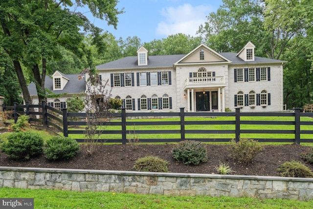 exterior space featuring a balcony, a lawn, and a fenced front yard