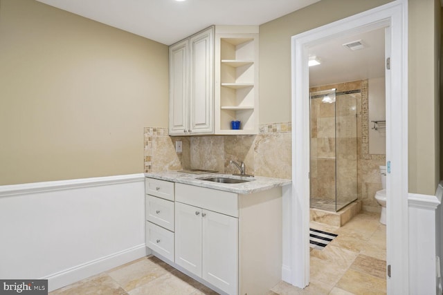 interior space with visible vents, a shower stall, vanity, and toilet