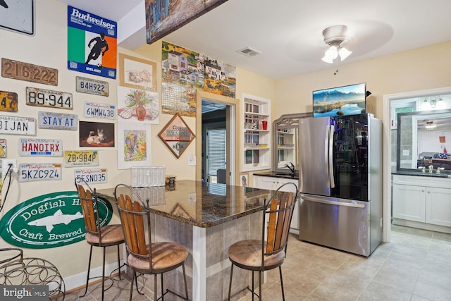 kitchen with dark stone counters, a kitchen breakfast bar, a peninsula, and smart refrigerator