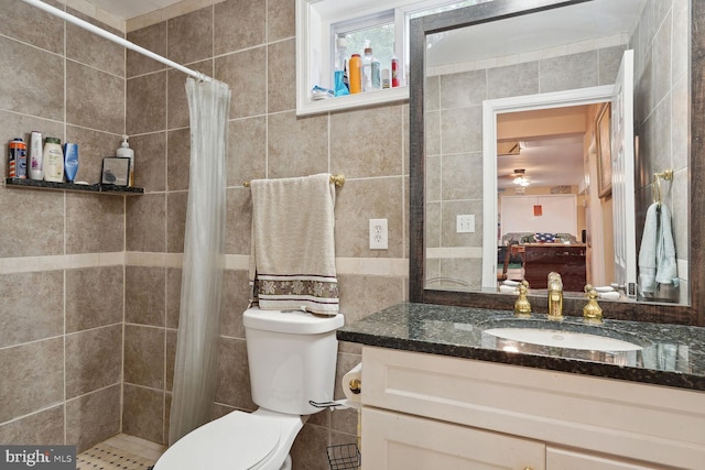 bathroom with tiled shower, toilet, tile walls, and vanity