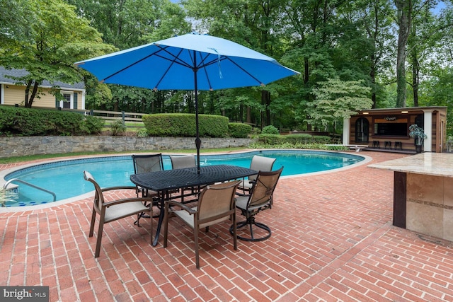 pool featuring outdoor dining area, a patio, and fence