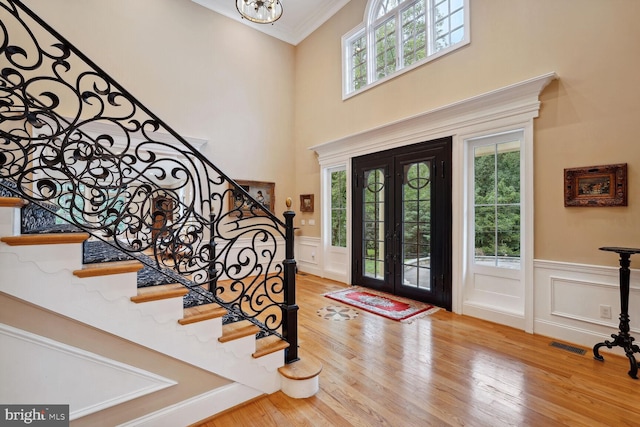 entryway with a wainscoted wall, wood finished floors, french doors, and visible vents