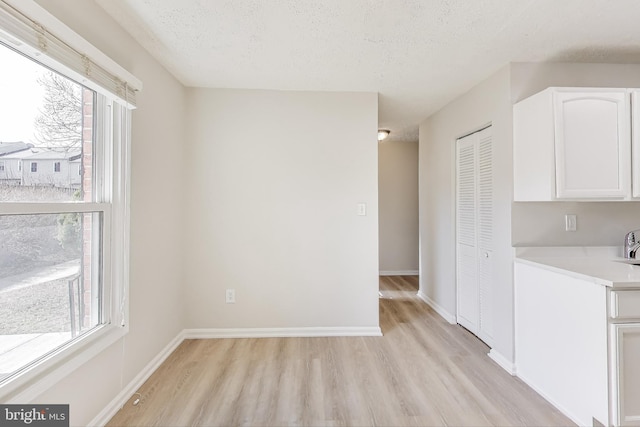 interior space with a wealth of natural light, light wood-type flooring, light countertops, and white cabinetry