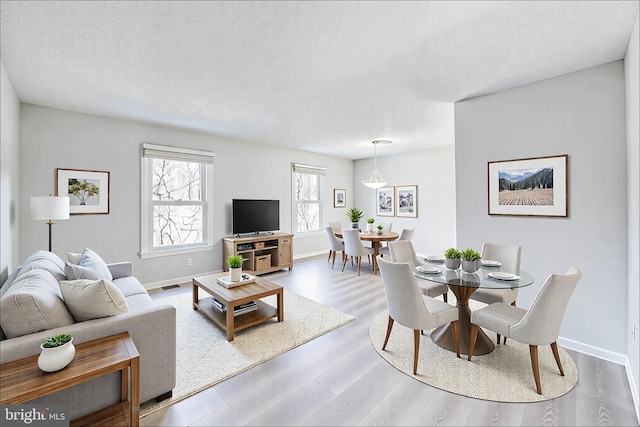 living room with visible vents, wood finished floors, baseboards, and a textured ceiling