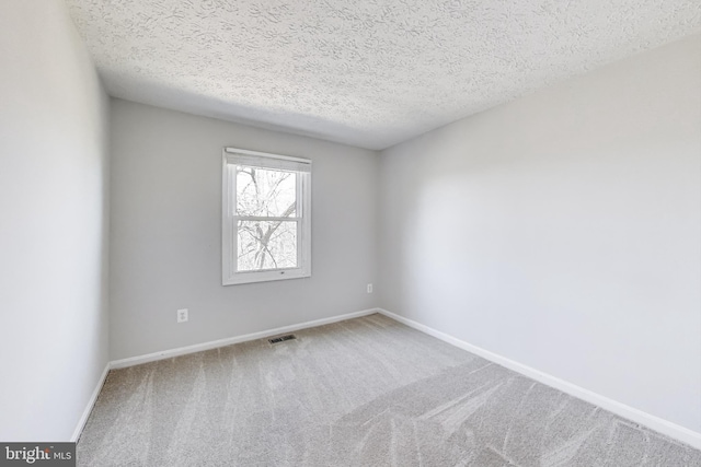 spare room with baseboards, visible vents, carpet floors, and a textured ceiling