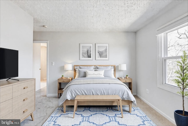 bedroom with light colored carpet, baseboards, and a textured ceiling