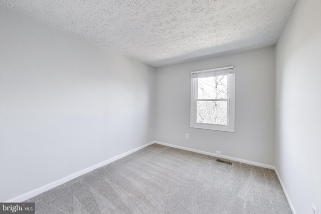 empty room featuring visible vents, baseboards, a textured ceiling, and carpet flooring