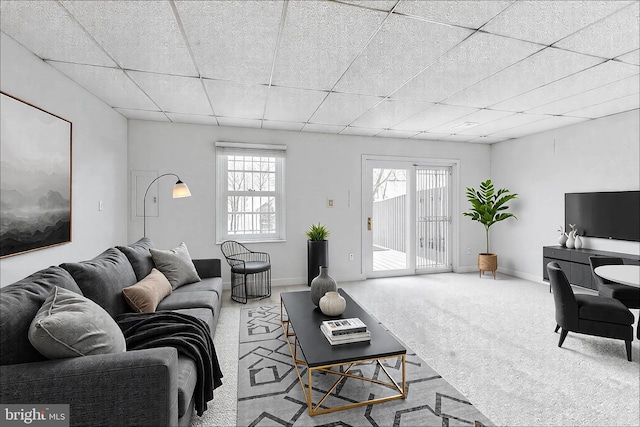 carpeted living room with a paneled ceiling and baseboards