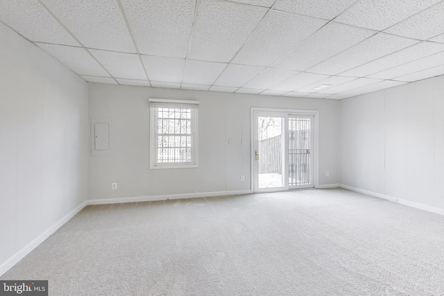 spare room with carpet, a healthy amount of sunlight, baseboards, and a drop ceiling