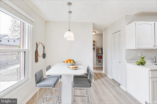 dining area with light wood-style floors, baseboards, and a textured ceiling