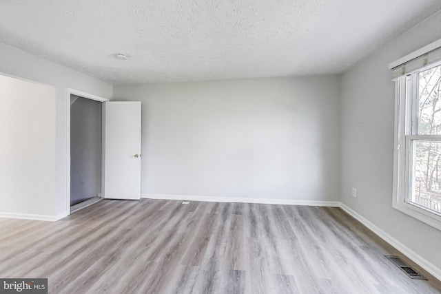 spare room featuring visible vents, plenty of natural light, and wood finished floors