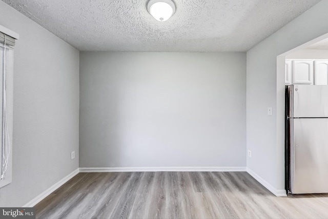 unfurnished room with baseboards, a textured ceiling, and wood finished floors