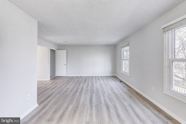 unfurnished room featuring a healthy amount of sunlight, baseboards, and light wood-style floors