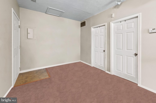 unfurnished bedroom with attic access, baseboards, visible vents, and carpet floors