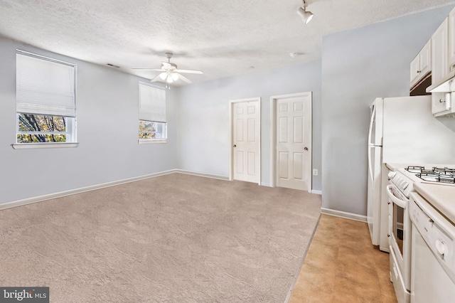 kitchen featuring light colored carpet, white range with gas stovetop, white cabinets, a textured ceiling, and a ceiling fan