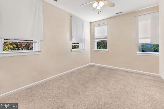 carpeted spare room featuring a ceiling fan, baseboards, and visible vents