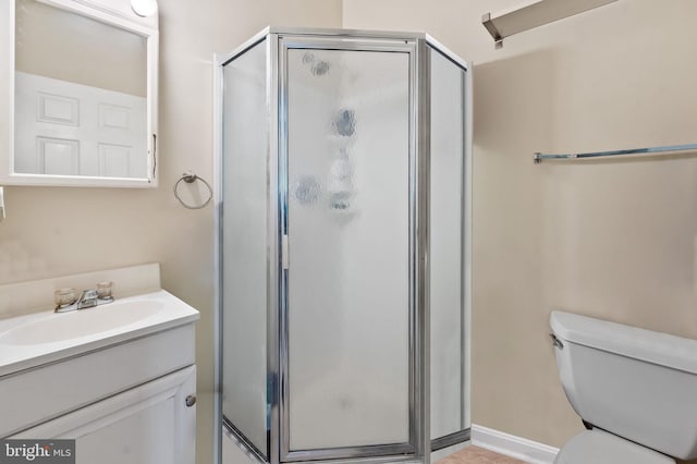 bathroom featuring vanity, a shower stall, and toilet