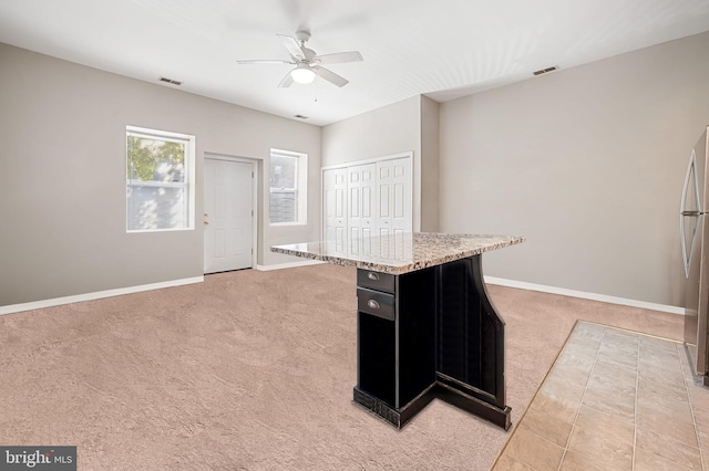 kitchen featuring dark cabinetry, baseboards, visible vents, and light carpet