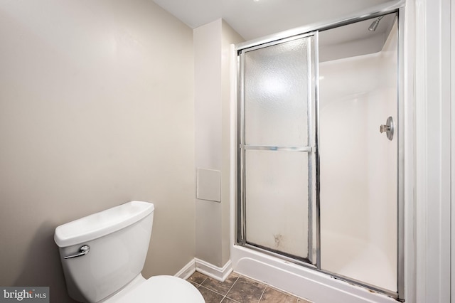 bathroom with tile patterned flooring, an enclosed shower, toilet, and baseboards