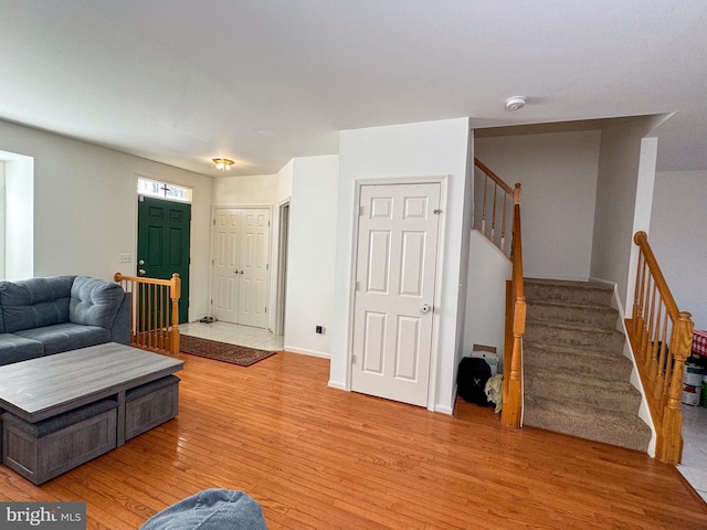 living area with stairway, baseboards, and light wood-style floors